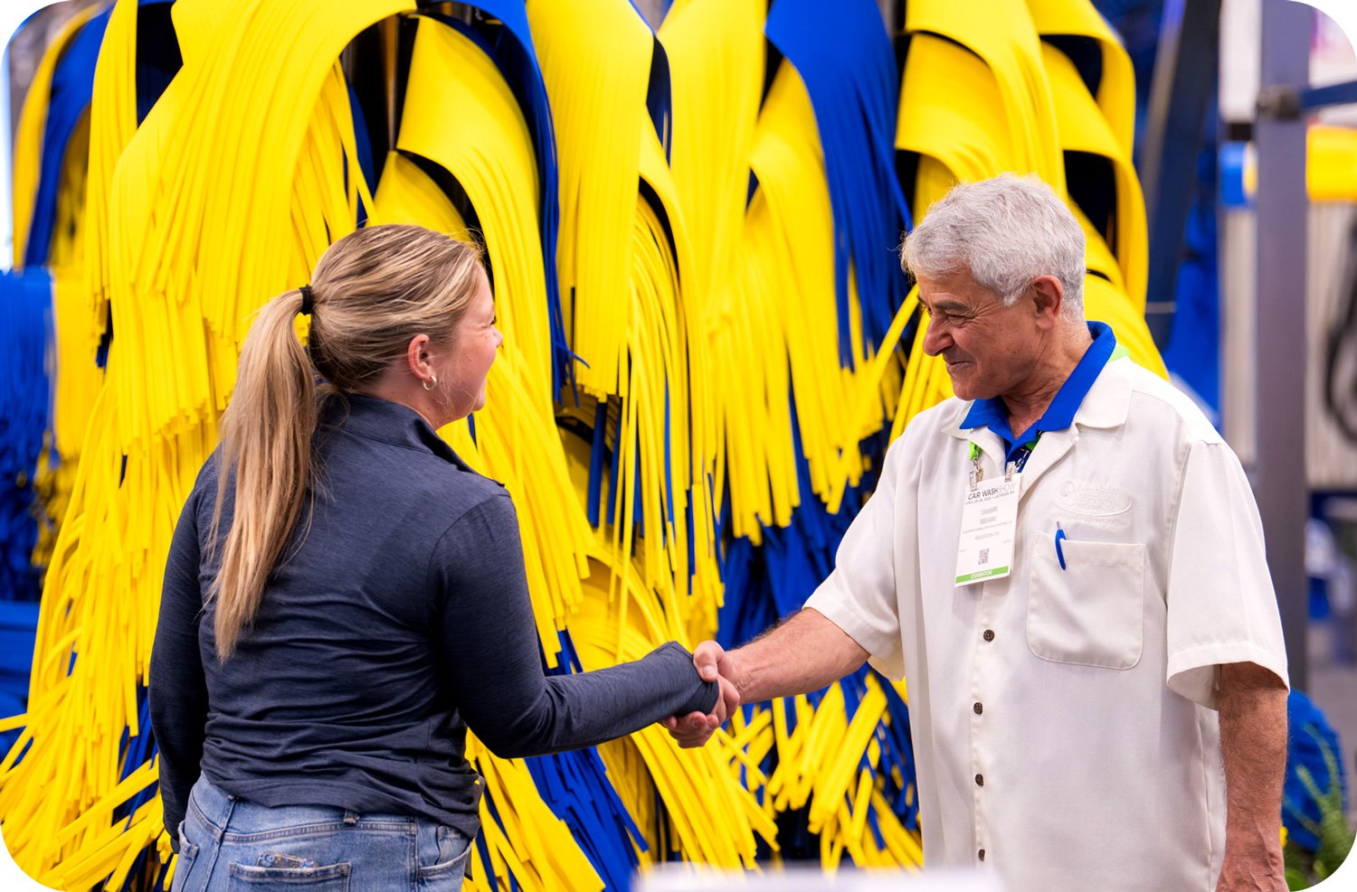 Trade show attendees meeting and shaking hands in front of equipment